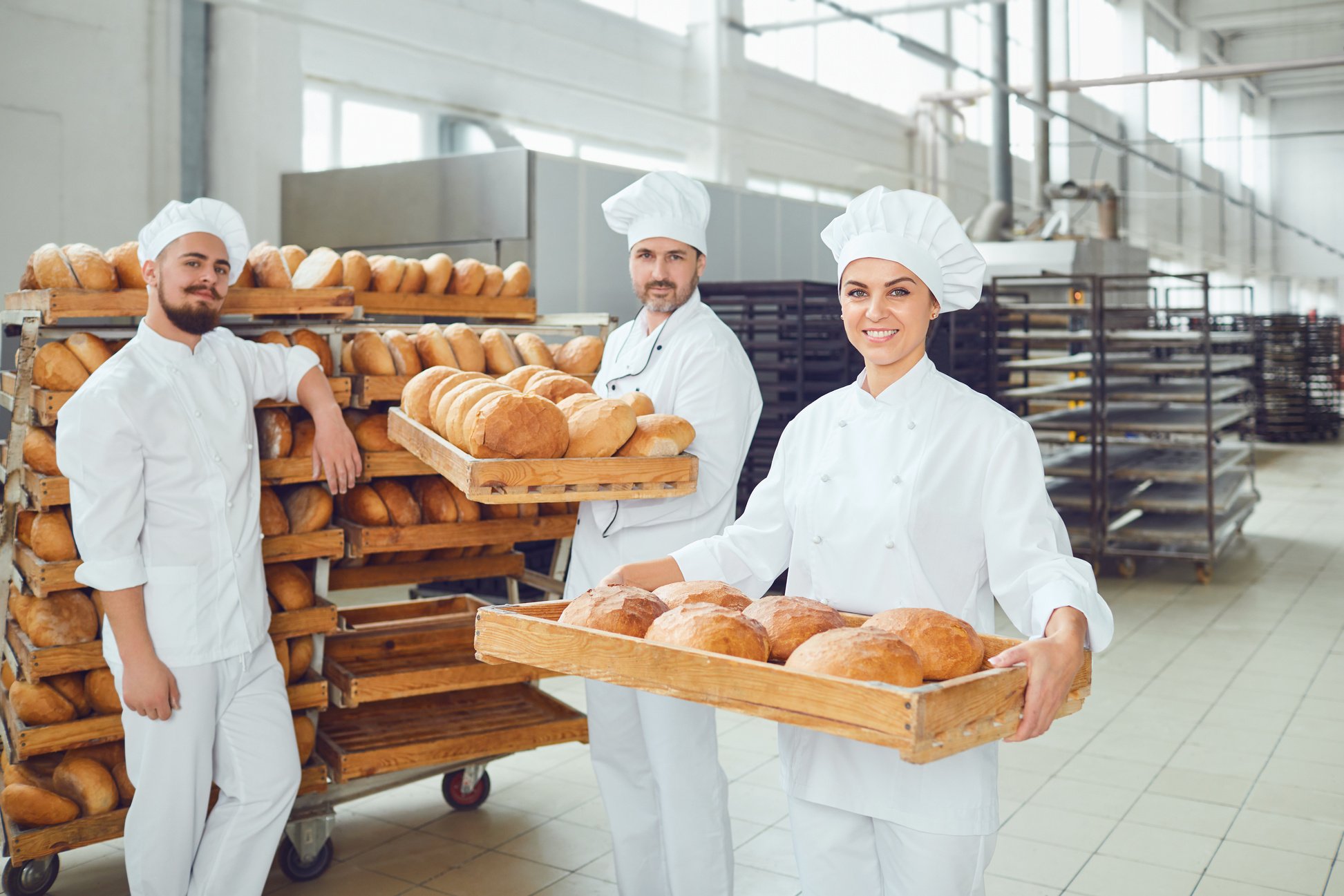 Bakers Hold a Tray with Fresh Bread in the Bakery